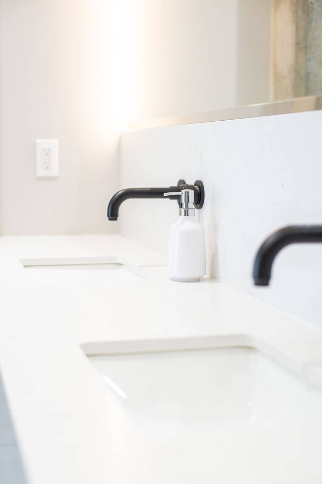 A clean, bright bathroom vanity with a white countertop and dark fixtures