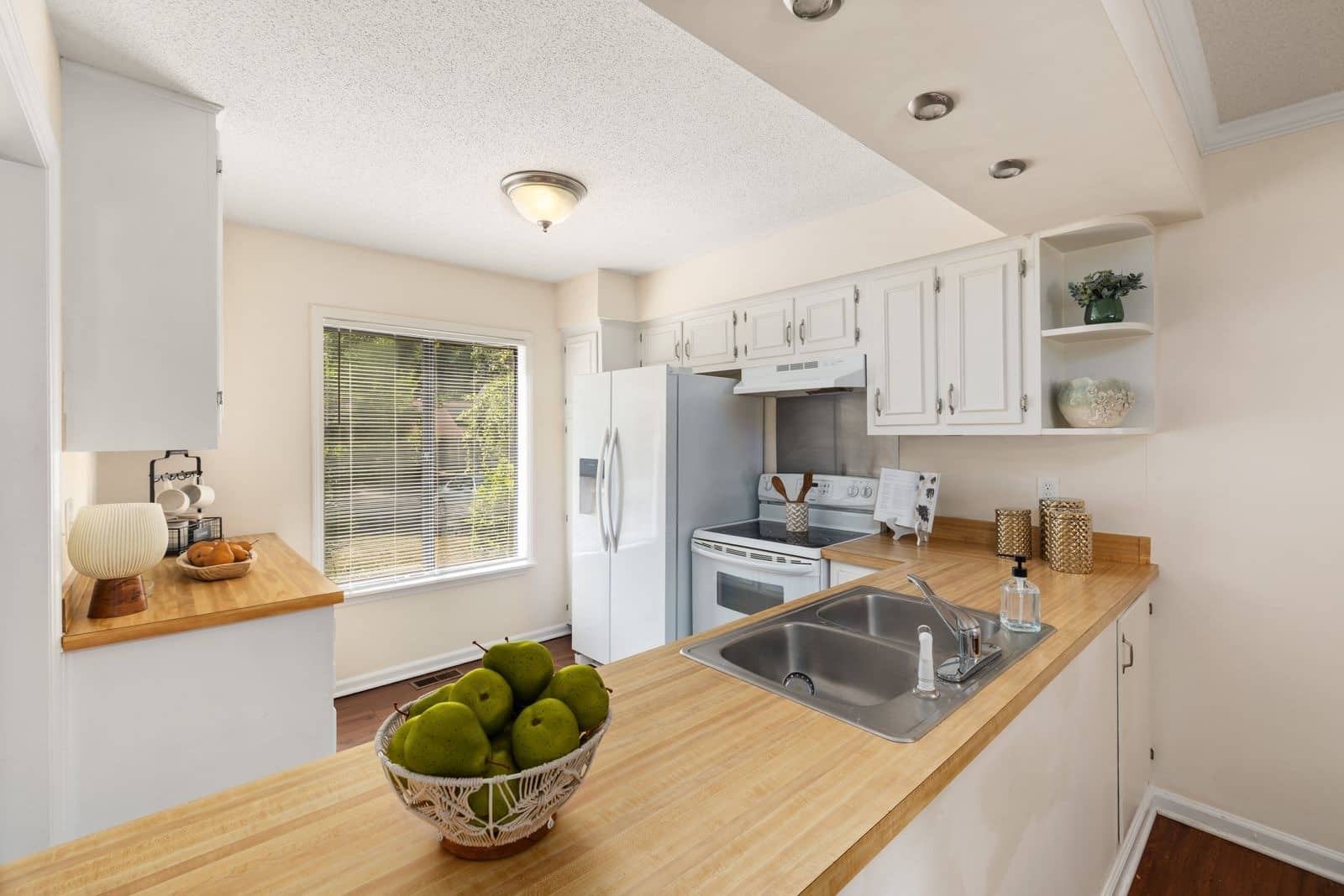 A full kitchen with white cabinets and wood counters, cleaned top to bottom