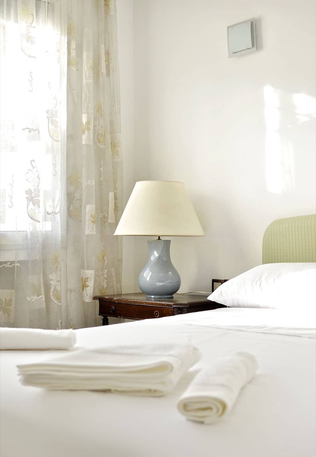 Fresh towels rolled and folded on a made bed, ready for a guest turnover
